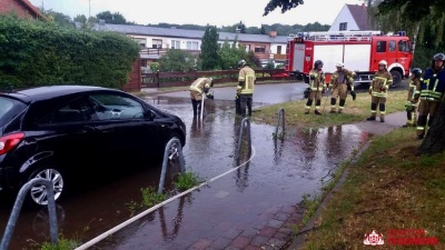 Feuerwehrleute pumpen eine überschwemmte Straße ab