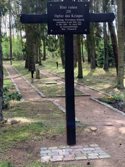 Kreuz auf einem Friedhof mit der Aufschrift “Hier ruhen 235 Opfer des Krieges - Flüchtlinge, Vertriebene, Soldaten verstorben in der Zeit vom 31. Okt. 1945 - 24. April 1947 im Quarantänelager Neu - Flessenow